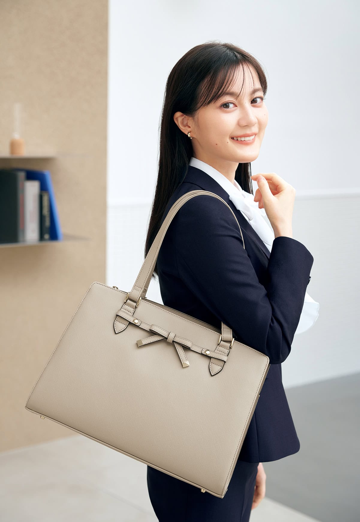 AOKIのリボンのついたバッグとパンツスーツのコーディネート写真