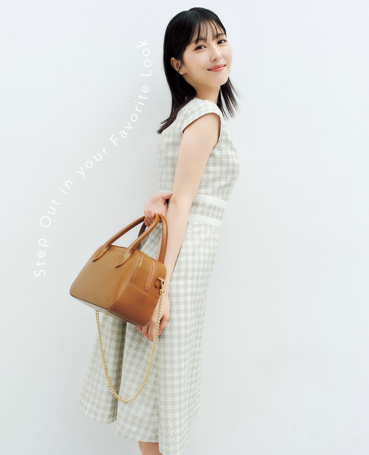 浜辺美波さんがキタムラのボストンバッグとレース調のドレスを着用し微笑むカット