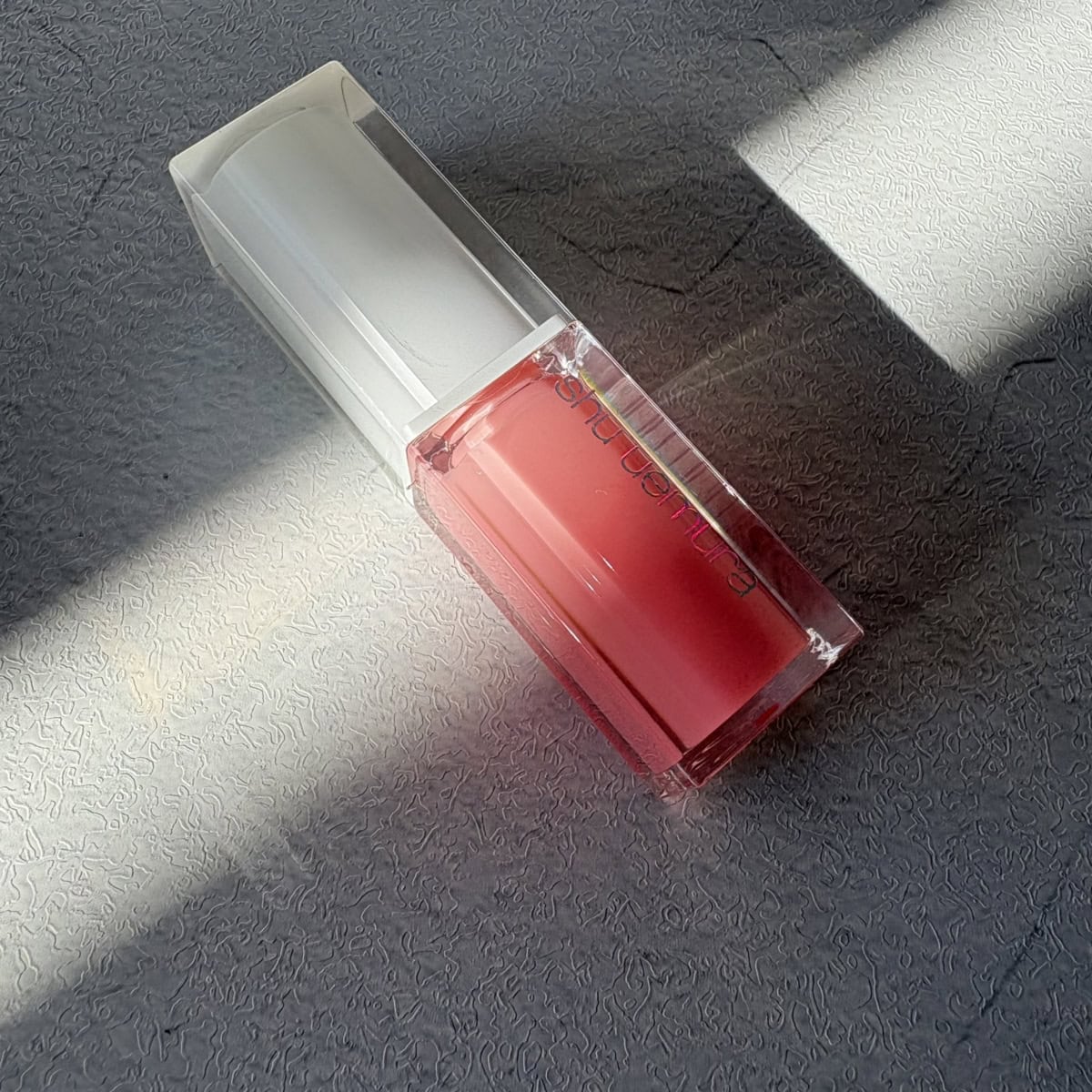 シュウ ウエムラのリップオイル「キヌケアCCオイル ピンクアイシング」。スキンケア発想で唇をケアしながら、自然なツヤをプラスしてくれる万能ピンクカラー。