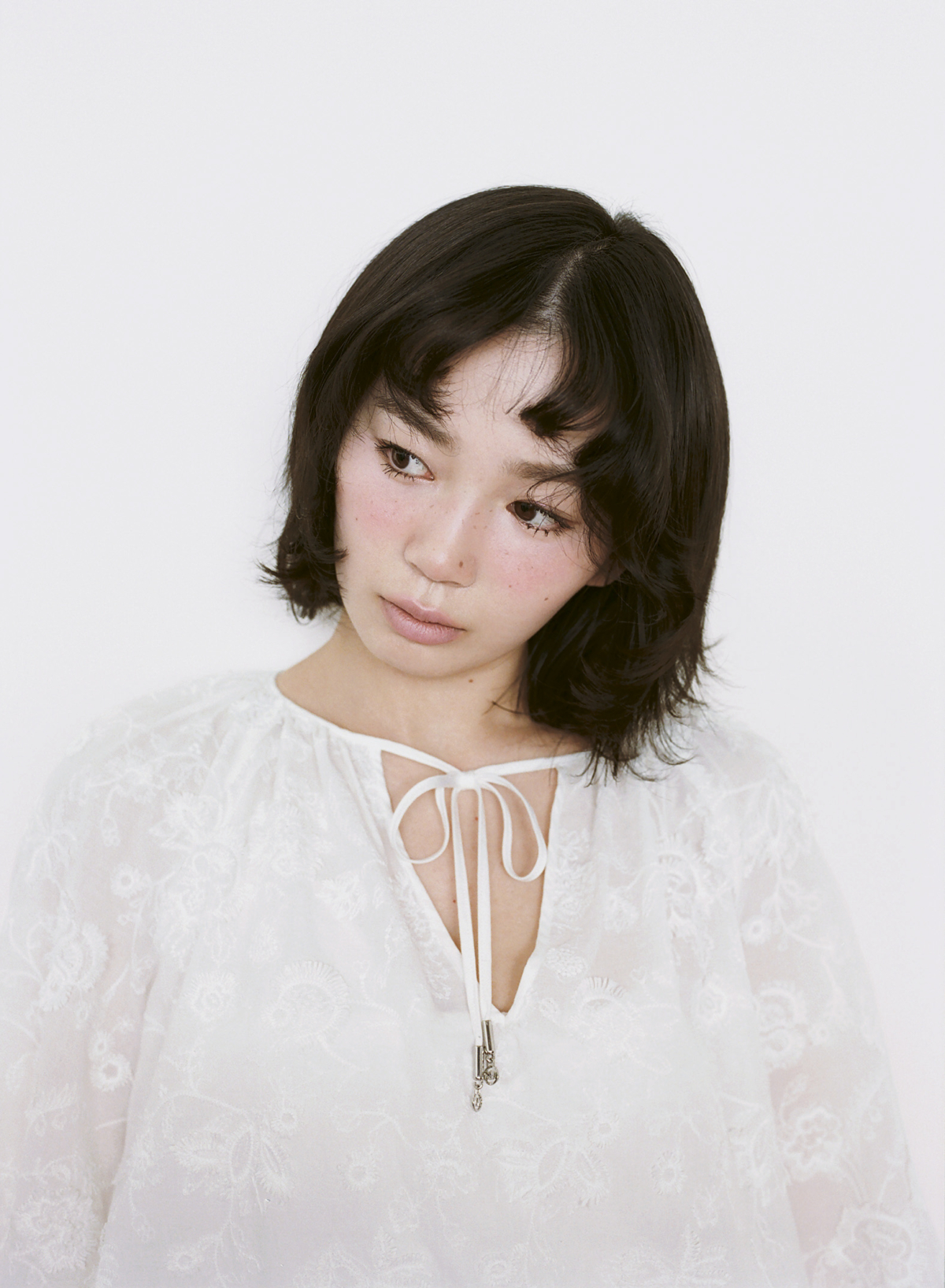 白いレースドレスを着て伏し目がちなポーズをとる宮﨑優。