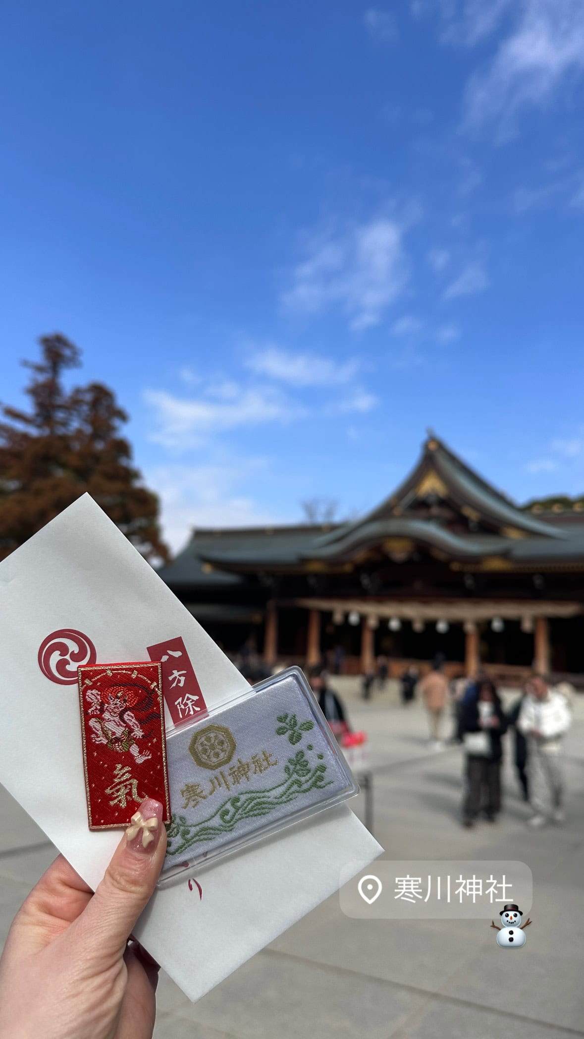 寒川神社の境内。購入したお守りを手に持っている平松さん。