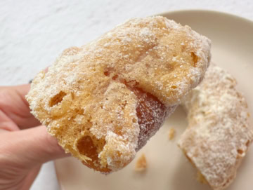 ドーナツの表面にオリジナルの液をつけてフライした後、シュガーをたっぷりとまぶしている