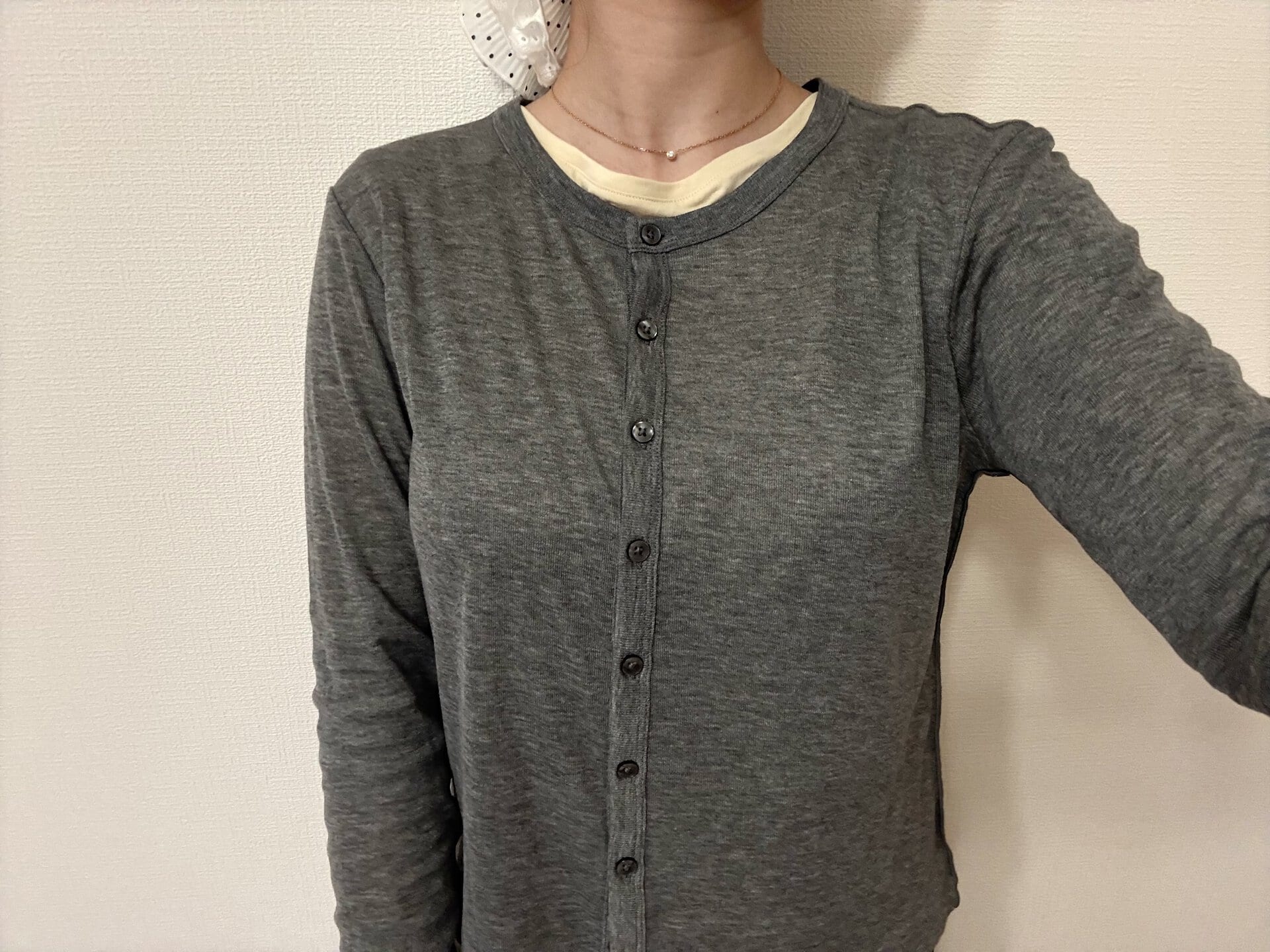 グレーのシアートップスの下に淡いイエローのインナーを忍ばせた差し色コーデ。