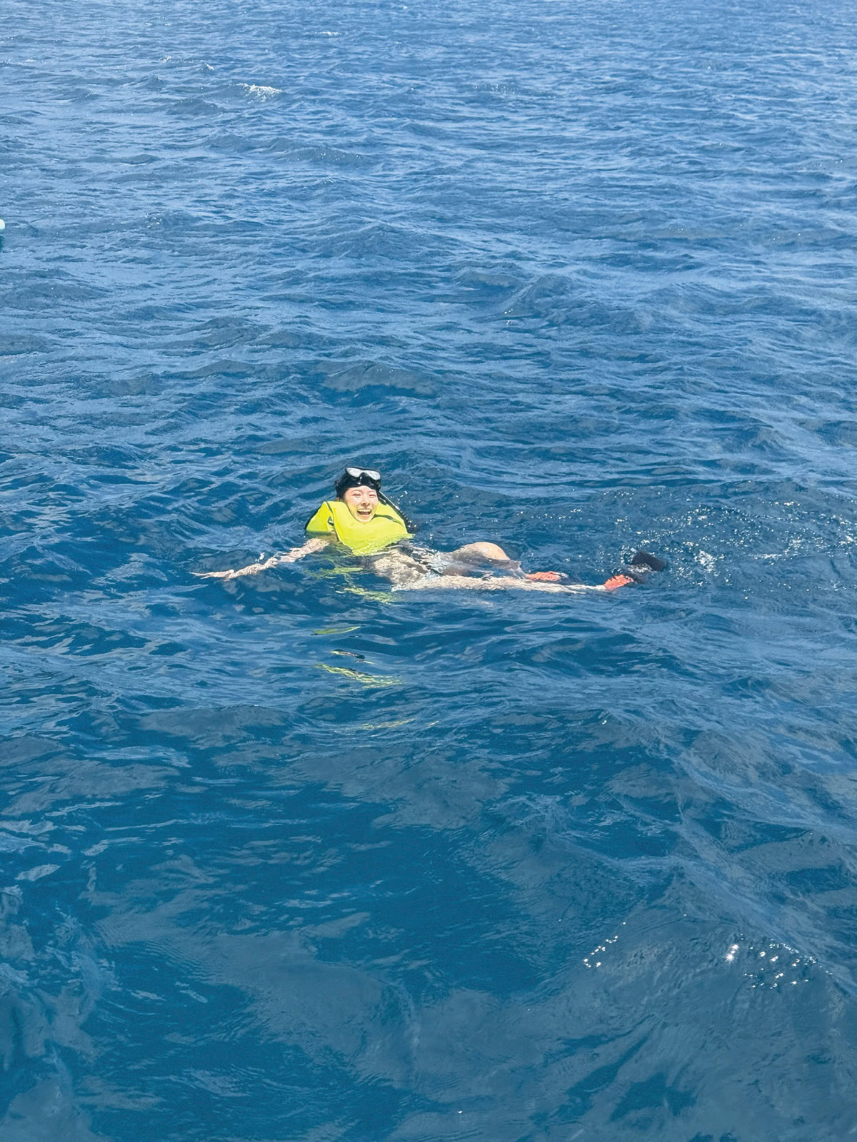 ライフジャケットを着て青い海で楽しそうに泳ぐミチさん