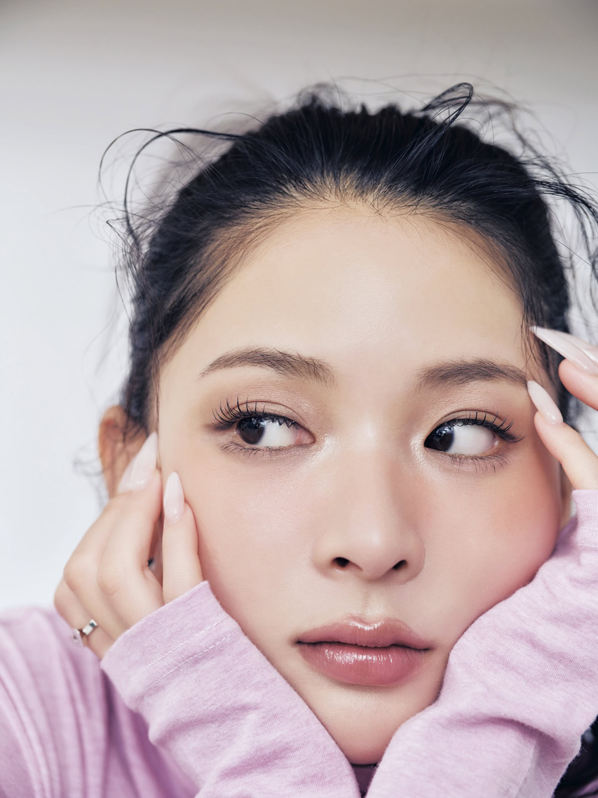 ピンクのタートルを着て頬に手をあてるモデルのミチ