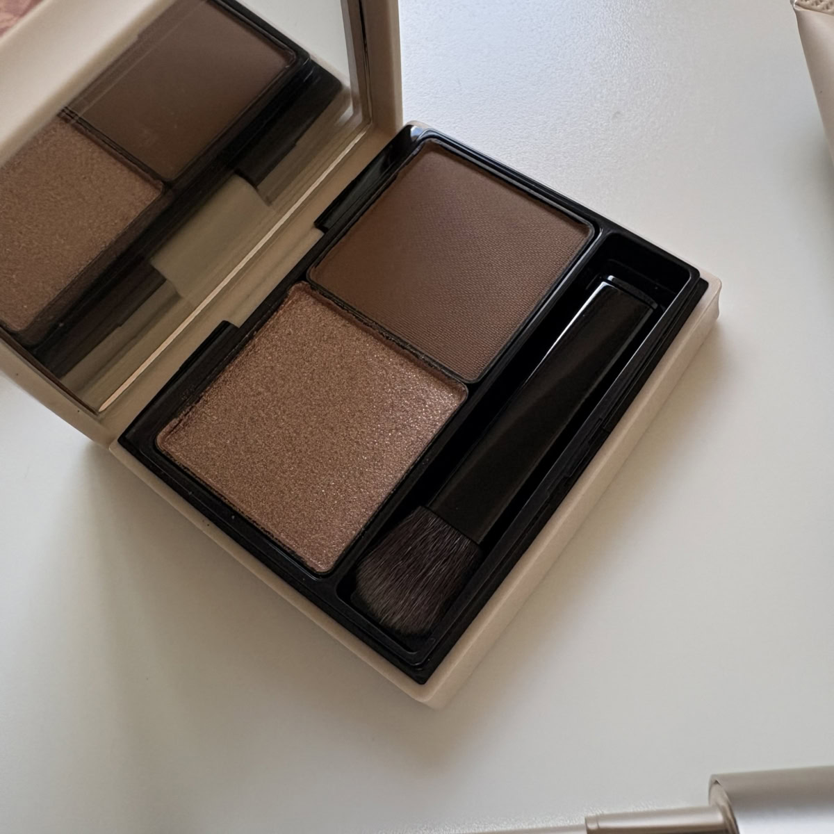 2色アイシャドウパレット「RMK ザ クワイエット プロヴォカター アイズ」のアップ。輝くブロンズブラウン(左)と、マットなダークブラウン(右)がセットされています。