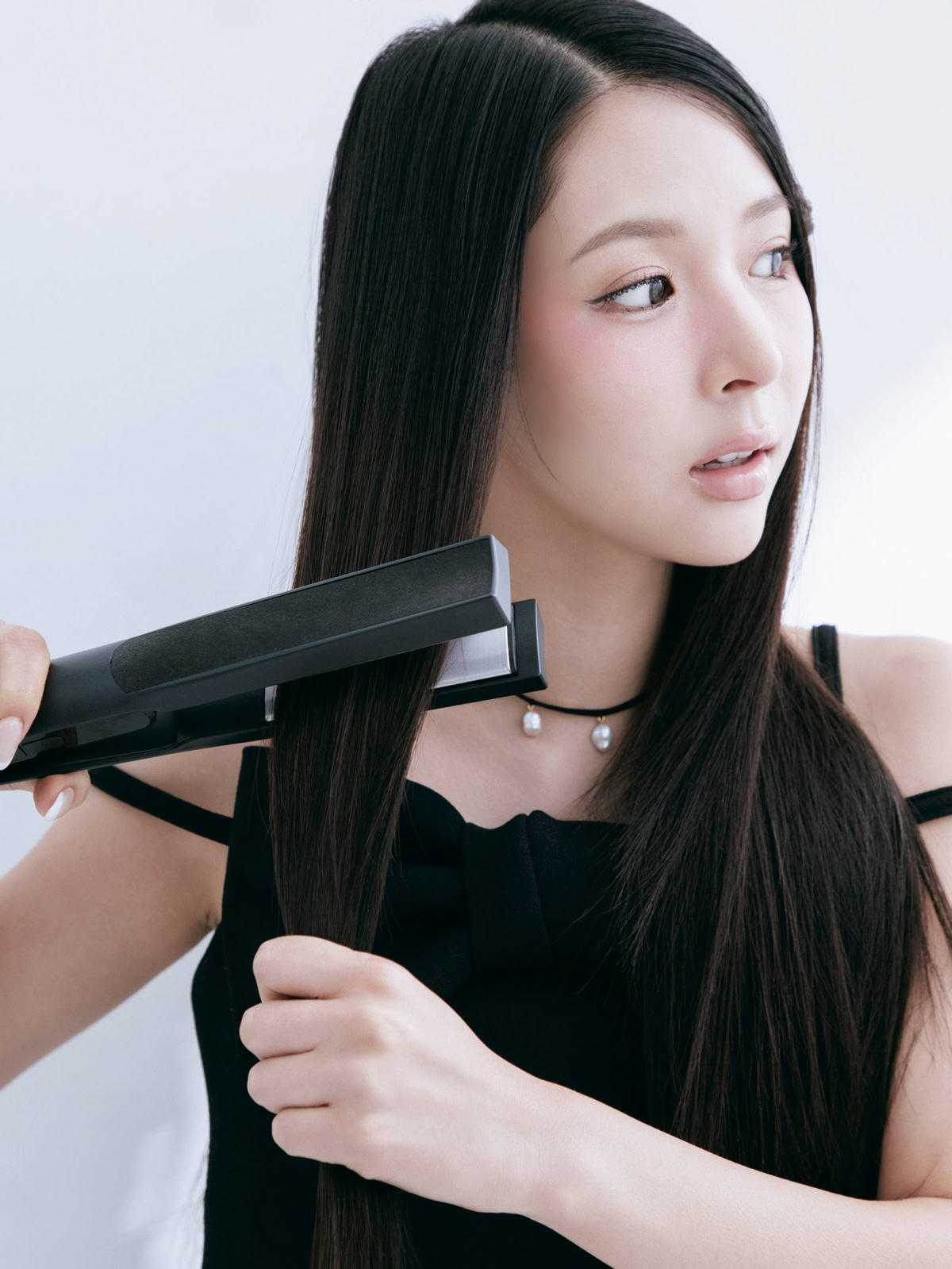 ストレートアイロンで髪の根元から毛先へ滑らせてスタイリングするミチ