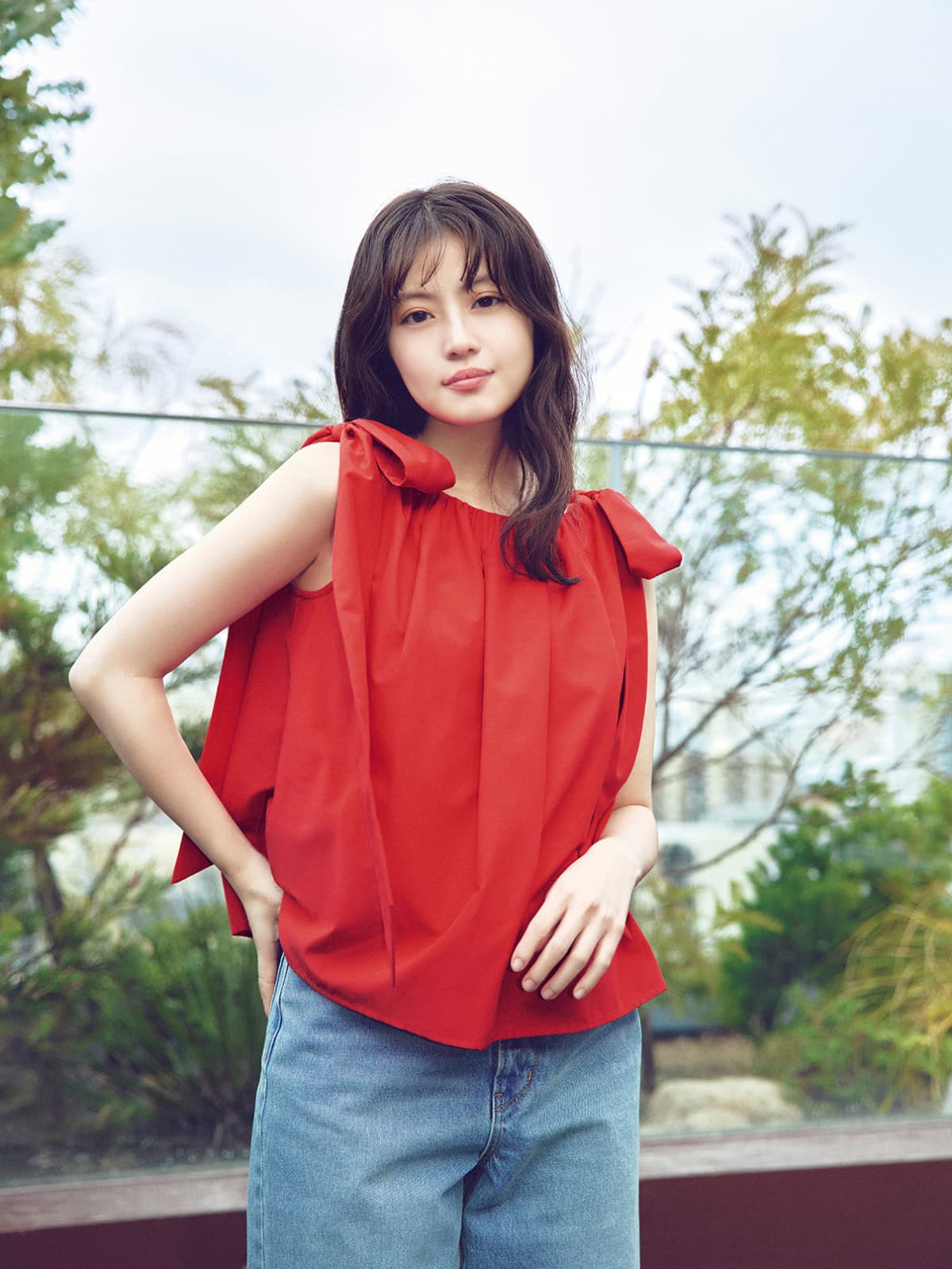 ナチュラルビューティーベーシックの赤いリボンブラウスとデニムを着て笑顔でポーズをとる今田美桜さん