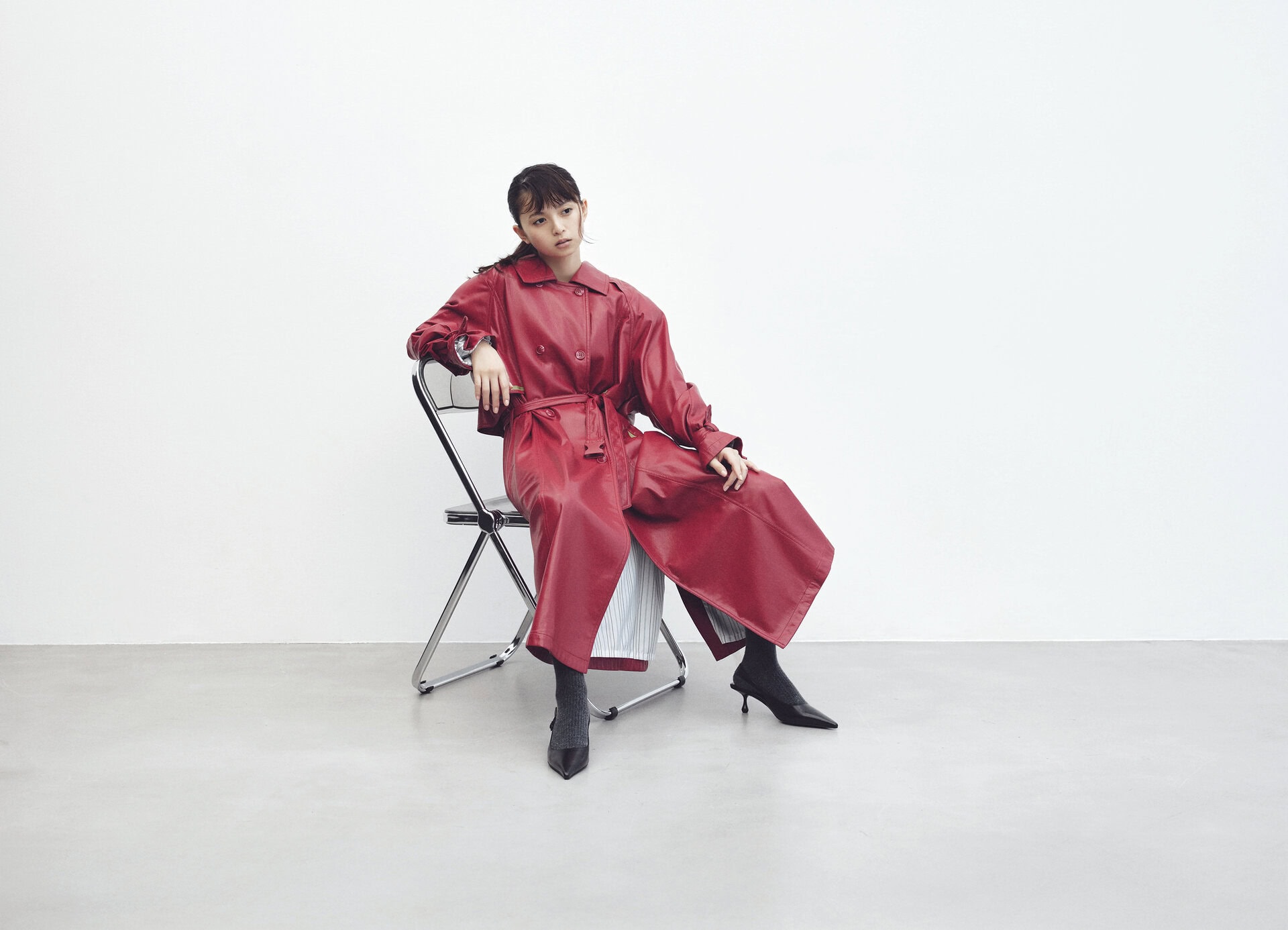 ドラマチックな赤のレザーコートを主役にしたセンシュアルな冬の装い。椅子に座りリラックスした表情を見せる、女優のような気品漂うカット。