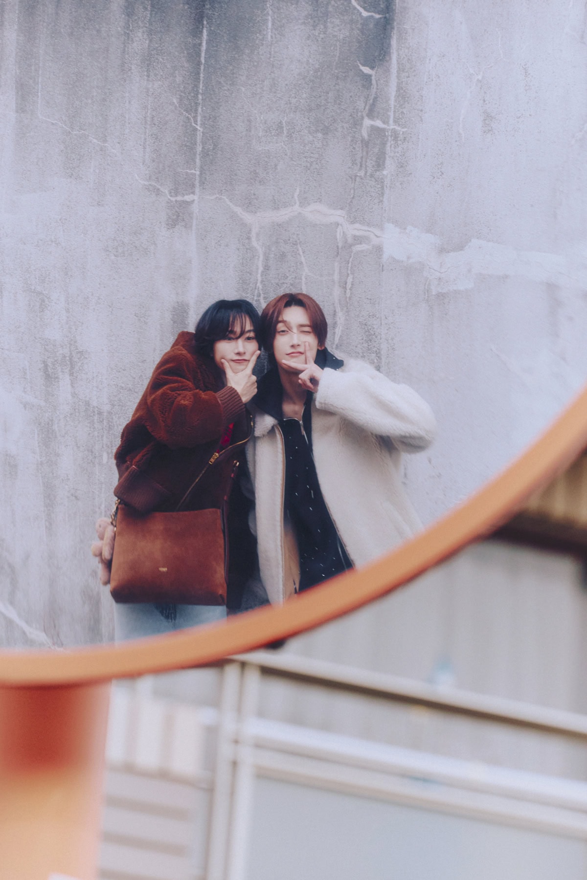 鏡越しに寄り添ってポーズを取る、ボアジャケットを着たROIROMの2人のナチュラルなツーショット