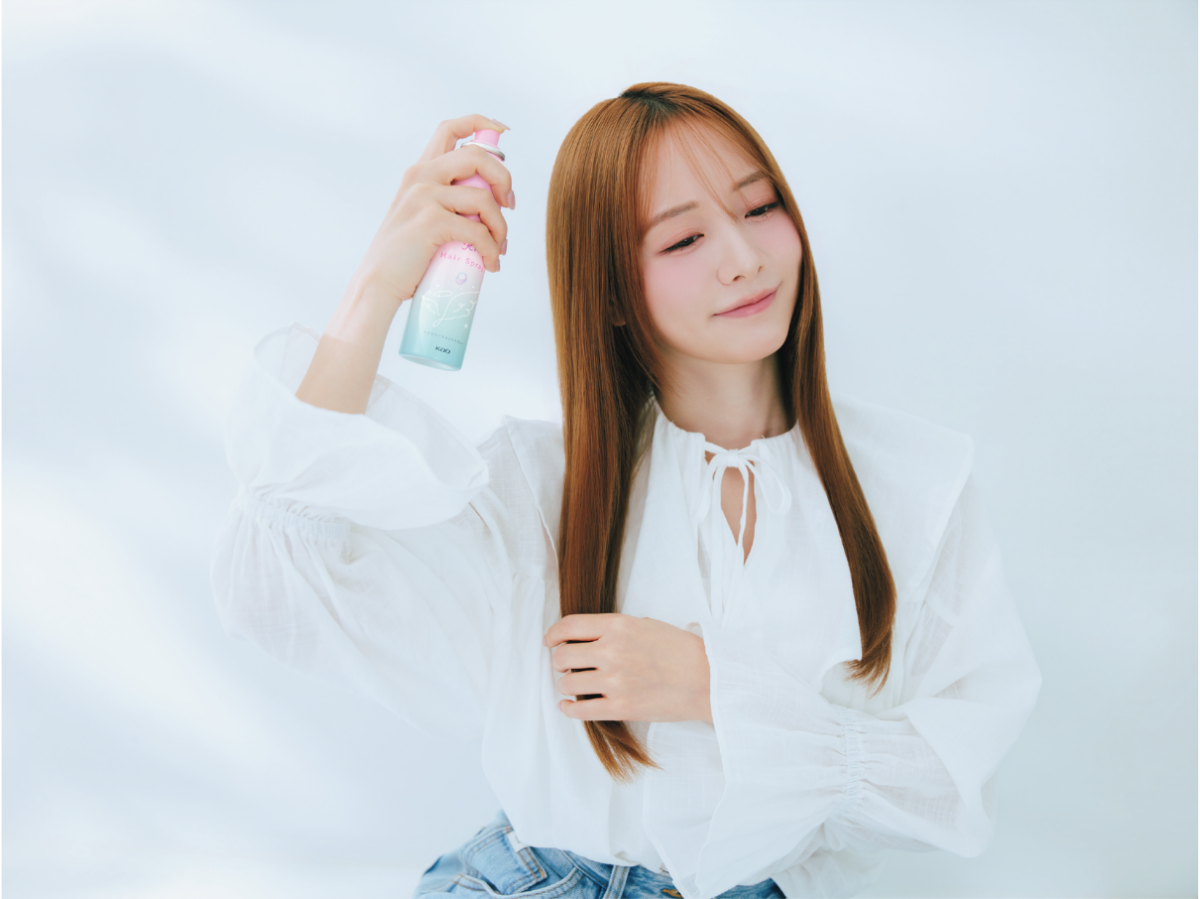 白いブラウス姿の森香澄さんが、エッセンシャル ふわりキラリスプレーを髪に吹きかけているカット。実際にスプレーを使って“天使のつやヴェール”を作る動作を実演。