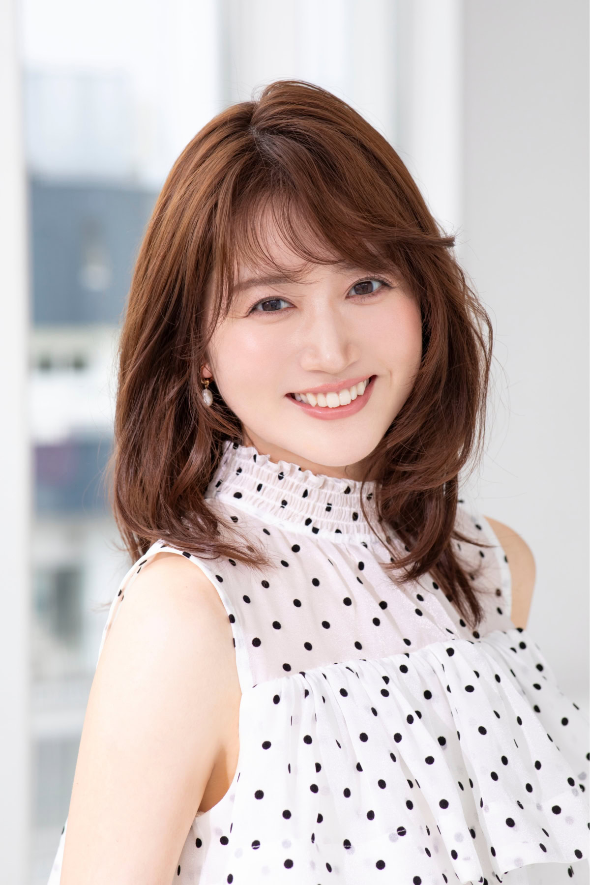 あいまるさんの上半身ポートレート。白地に黒のドット柄があしらわれたノースリーブブラウスを着用し、カメラに向かって明るい笑顔を見せている。肩までのブラウンヘアを自然に下ろし、やわらかな光が差し込む室内で撮影された、上品で親しみやすい雰囲気の一枚。