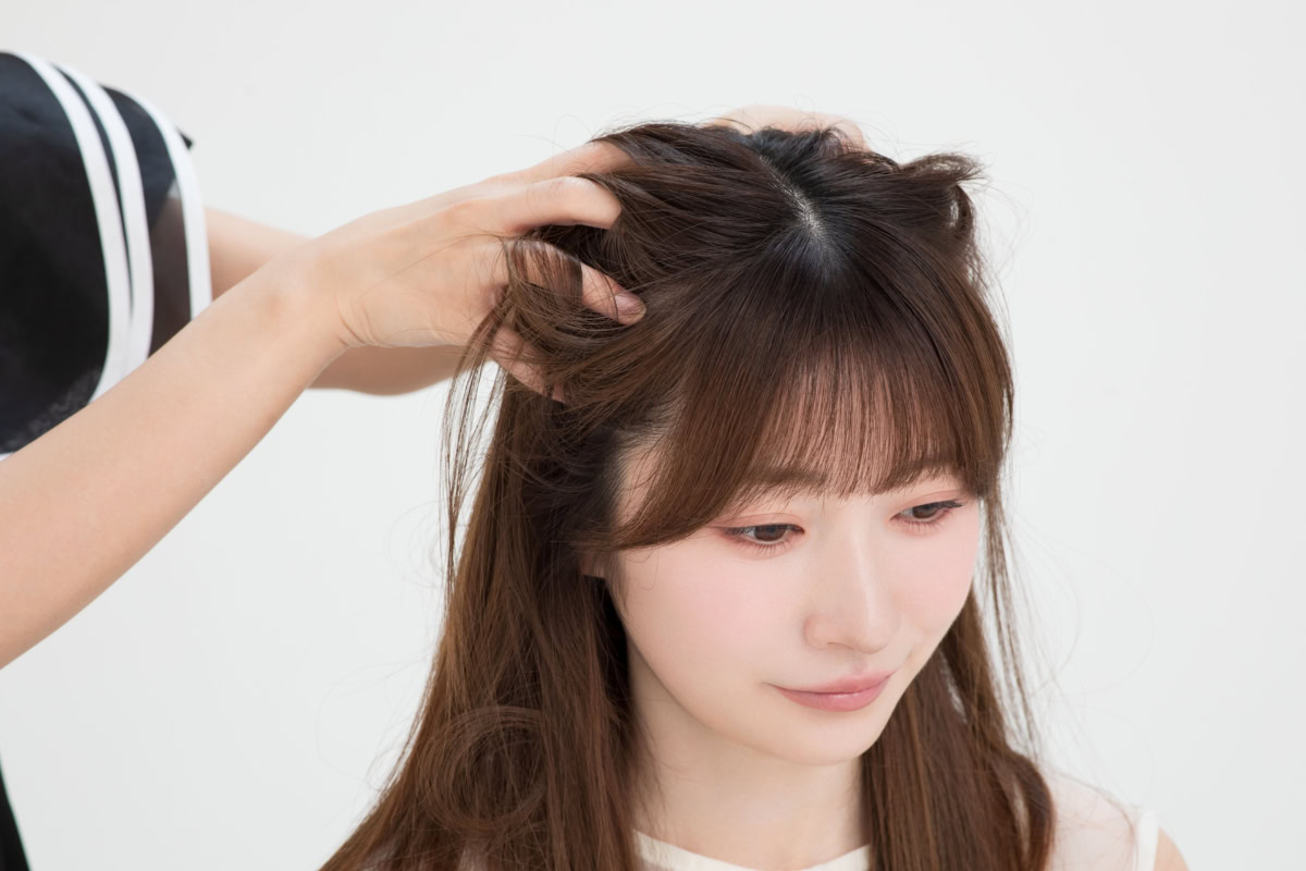 頭皮や髪の根元に指を入れ、全体にスプレーしたドライシャンプー「バティスト」をマッサージするようになじませる工程