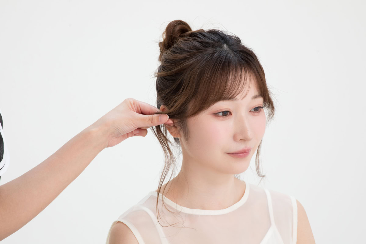 指についたパウダーを刷り込むように、耳前の後れ毛の根元を指先でつまんで形を整える工程