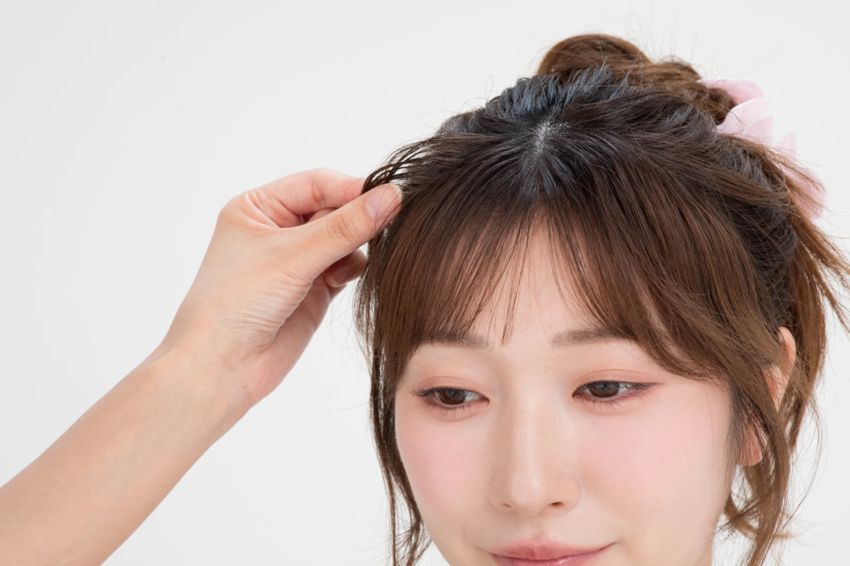 顔まわりの髪の立ち上がりカーブを指先でつまみ、パウダーを揉み込んでエアリーな立体感を作る最終仕上げ