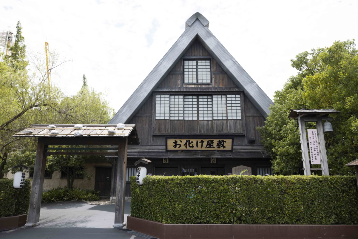 大きな合掌造り風の木造屋根と「お化け屋敷」の文字が印象的な和風アトラクション外観