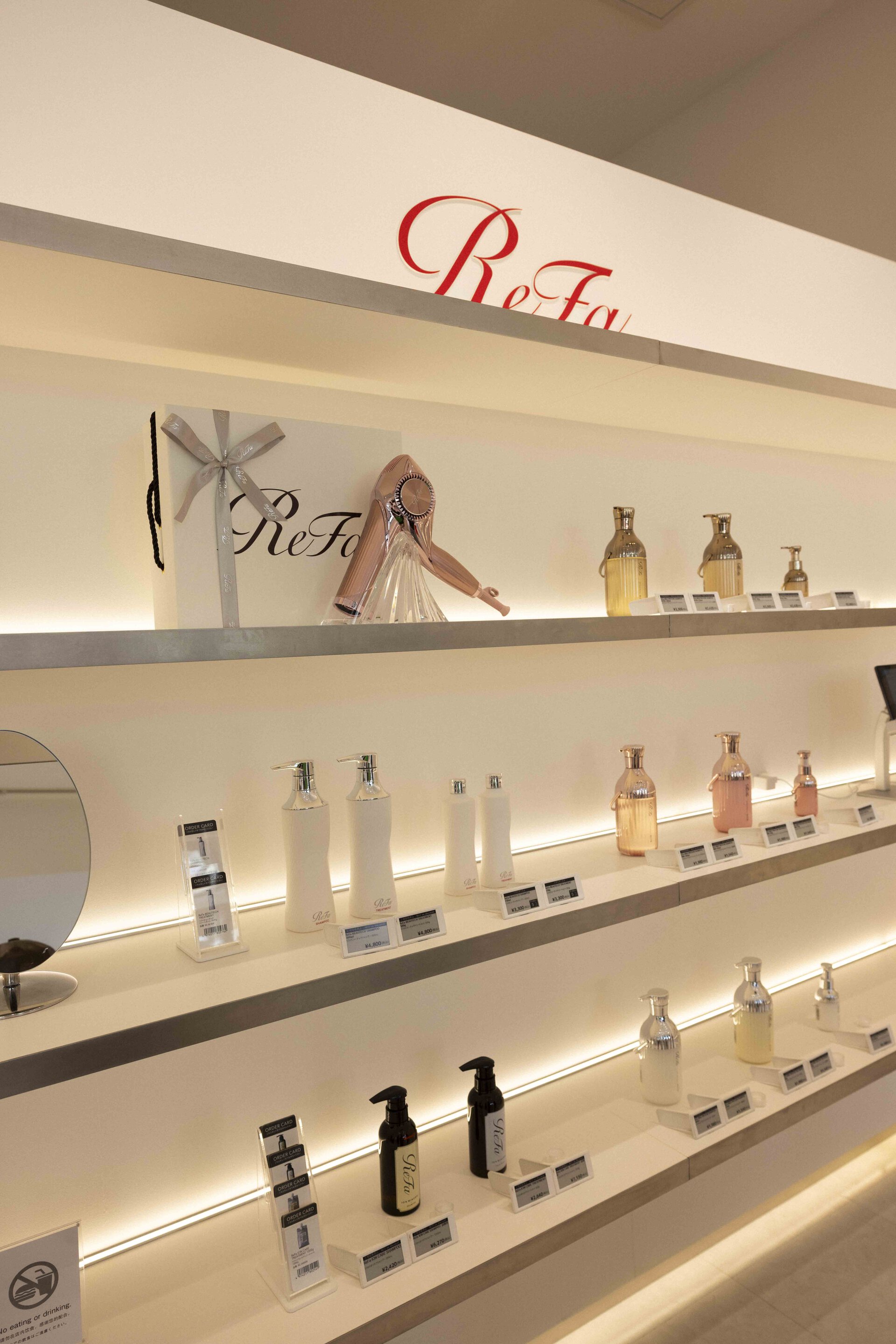 ReFaジャズドリーム長島店の白を基調とした洗練されたヘアケア・スキンケアアイテムの陳列棚